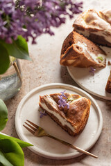 One piece of chocolate cheesecake layered with brownie and cottage cheese. Chocolate cake sliced on brown textured background with lilac flowers rustic style