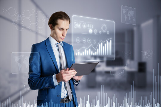 Attractive young businessman using tablet with glowing business chart hologram on blurry office interior background. Financial growth, future and success concept. Double exposure. - Powered by Adobe
