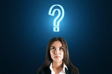 Thoughtful face of a businesswoman closeup and a sign of question over her head on a dark blue...