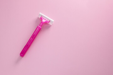 Disposable shaving razor for hair removal on pink background