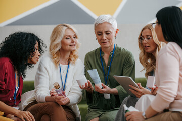 Group of mature women examining beauty products during specialized conference