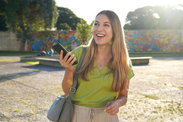 Latin young woman using mobile phone outdoor with colorful background on sunset