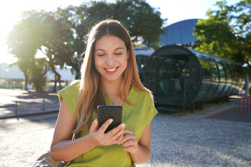 Portrait of happy smiling young woman using mobile phone in Curitiba, Brazil