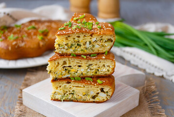 Egg and Onion bread. Sliced Breakfast Pie with hard boiled egg and spring onion filling served on a white wooden board. Selective focus, horizontal, closeup