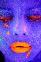 Neon paint, beauty and woman face closeup with dark background and creative cosmetics. Glow, rave makeup and psychedelic cosmetic of a female model with unique and creativity with art in studio