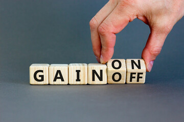 Gain on or off symbol. Businessman turns wooden cubes and changes word Gain off to Gain on. Beautiful grey table grey background. Business and gain on or off concept. Copy space.