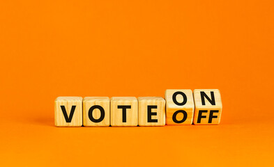 Vote on or off symbol. Businessman turns wooden cubes and changes word Vote off to Vote on. Beautiful orange table orange background. Business and vote on or off concept. Copy space.