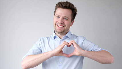 European young man shows a heart sign and confesses love