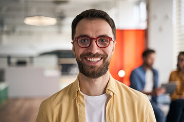 Portrait of confident smiling businessman, middle aged freelancer wearing stylish red eyeglasses standing in office. Happy smart student looking at camera in university campus, education concept