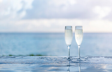 Two glasses of champagne on the side of the infinity pool against the backdrop of a sunset in the Maldives