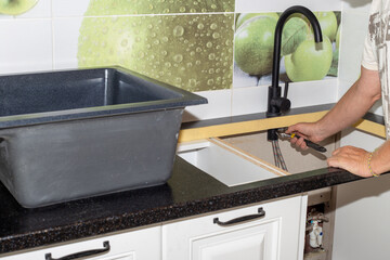 Installation of plumbing fixtures and sinks in the kitchen. The man is fixing the faucet