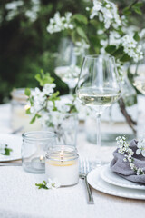 Romantic elegant luxury wedding table decor with white fresh spring blooming cherry apple tree flowers. Glass, candles, floral decoration for special marriage holiday event. No plastic zero waste