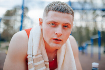 Fatigued athlete taking a breather during a grueling outdoor workout, sweat soaking his shirt....
