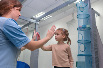 Child girl give five physiotherapist during sensory integration session. The concept of happiness...