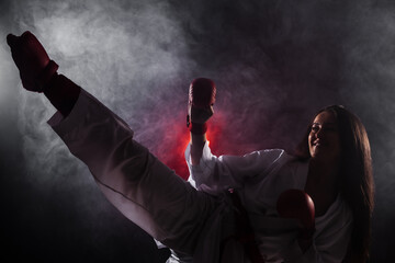 girl exercising karate leg kick against red fog background