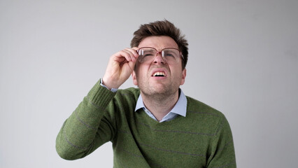 European young man with poor vision peers through his glasses, trying to discern the information...