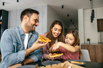 Happy family eating pizza at home - 602431495