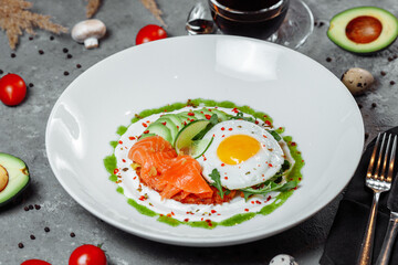 Poached eggs on top of smashed avocado on sourdough toast with smoked salmon. Healthy breakfast with plate on table. Top view. Copy space to right