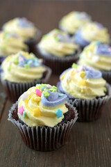 Yellow and purple easter cupcake on wooden background