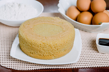 Cake freshly prepared and ready to decorate with ingredients behind.