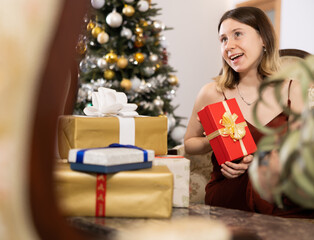 Fototapeta na wymiar Young woman, being in anticipation of the holiday, prepares Christmas presents for guests at home