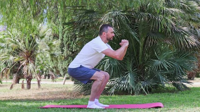 A middle aged athletic man doing sit up exercisee on a mat in a city park. Fitness workout outdoors.