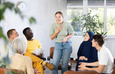 Group of multiethnic people doing discussing while sitting on chairs in circle in office