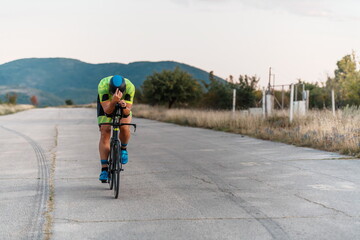  Triathlete riding his bicycle during sunset, preparing for a marathon. The warm colors of the sky...