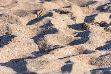 Texture of beach sand with contrasting light and shadow.