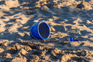 Blade made of blue plastic toy very dirty in the sand on the beach.