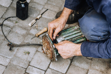 Male professional worker, electrician, electromechanic repairing an old rusty electric motor in a workshop. Photography, close-up portrait, equipment repair.