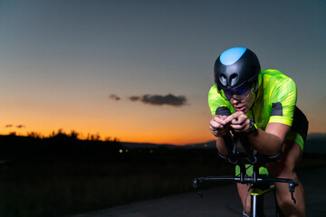 Obraz na płótnie Canvas A triathlete rides his bike in the darkness of night, pushing himself to prepare for a marathon. The contrast between the darkness and the light of his bike creates a sense of drama and highlights the