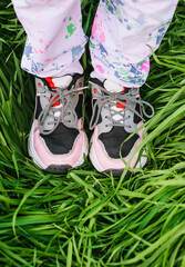 A girl, a child in sports leather multi-colored sneakers stand on the grass, walk, outdoor recreation. Photography, close-up portrait, top view, leisure, sports.