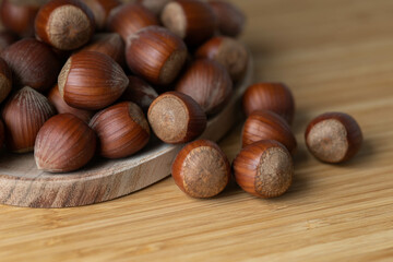 Obraz na płótnie Canvas handful of hazelnuts on wooden bowl and wooden table, very healthy nuts