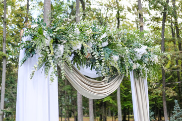 wedding ceremony in the forest with decorated arch and chairs	