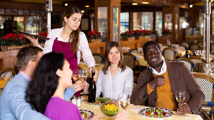 Smiling couple on friendly meeting over dinner with wine in restaurant