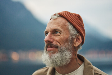 Happy older bearded man standing in nature park enjoying landscape. Smiling active mature traveler...