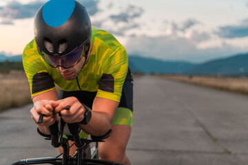  Close up photo of triathlete riding his bicycle during sunset, preparing for a marathon. The warm...