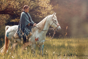Portrait of a woman on her american native decorated white arabian horse in spring outdoors