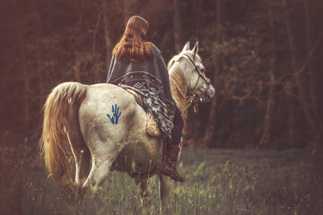 Portrait of a woman on her american native decorated white arabian horse in spring outdoors
