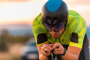  Close up photo of triathlete riding his bicycle during sunset, preparing for a marathon. The warm...