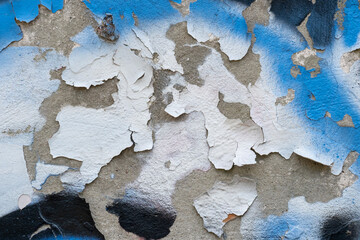 Peeling black and white with blue paint on an old concrete wall