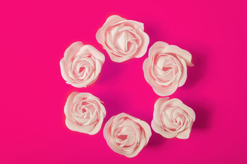 Round frame from beige soap roses on bright pink background, top view, flat lay. The concept of skin care, beauty, Valentine's Day.