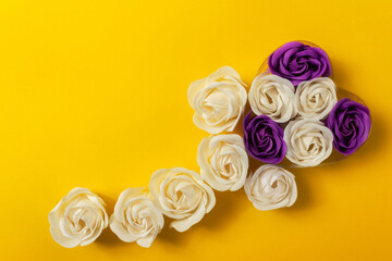 Floral composition: flower from white and purple soap roses, gift for Valentine's Day on yellow background with copy space, top view. The concept of love, skin care, beauty, Valentine's Day.