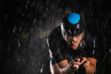 A triathlete braving the rain as he cycles through the night, preparing himself for the upcoming...
