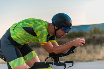  Close up photo of triathlete riding his bicycle during sunset, preparing for a marathon. The warm...