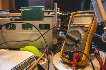 Electronics expertise: multimeter, open electronic equipment and a notebook on a table