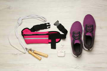 Flat lay composition with pink waist bag on white wooden table