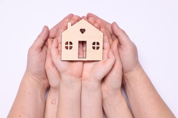 Home security concept. Family holding house model on white background, top view