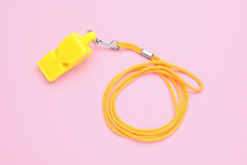 One yellow whistle with orange cord on pink background, top view
